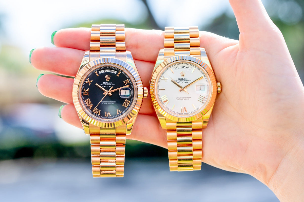 Gold Rolex Day Date watches held outdoors