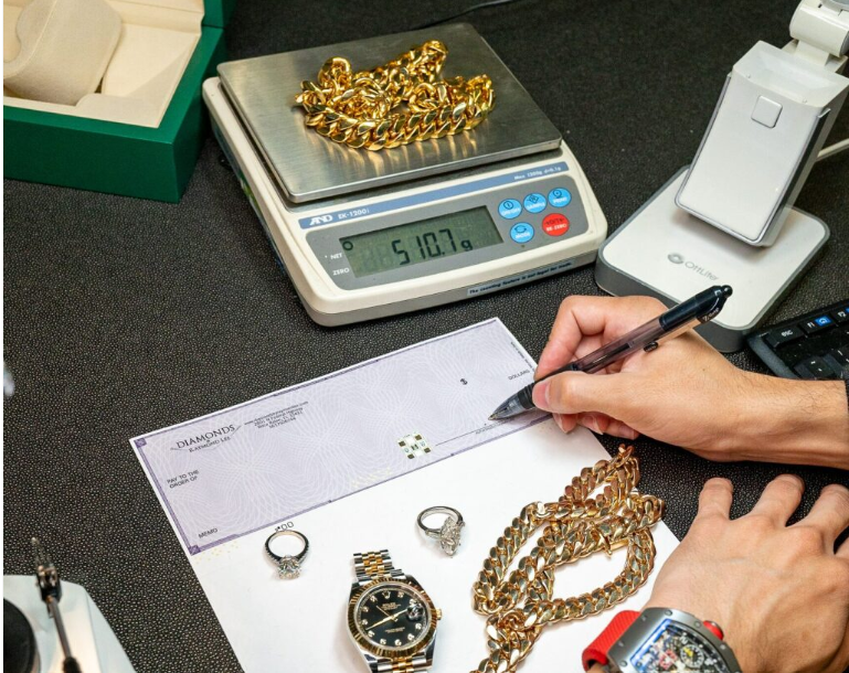 Jewelry appraisal with gold chain weighed on scale and luxury items evaluated at a jewelry store.