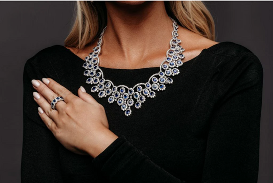 Woman wearing an elegant sapphire and diamond necklace with matching ring, showcasing luxury fine jewelry craftsmanship and timeless design.