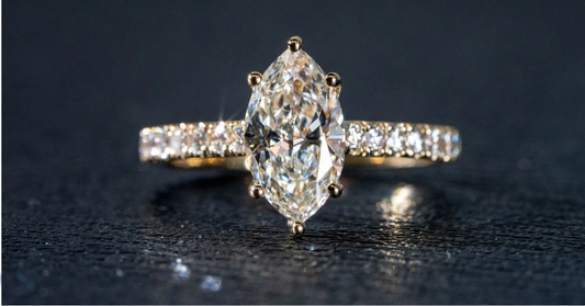 Marquise cut diamond engagement ring with pavé band in yellow gold, luxury fine jewelry close-up.