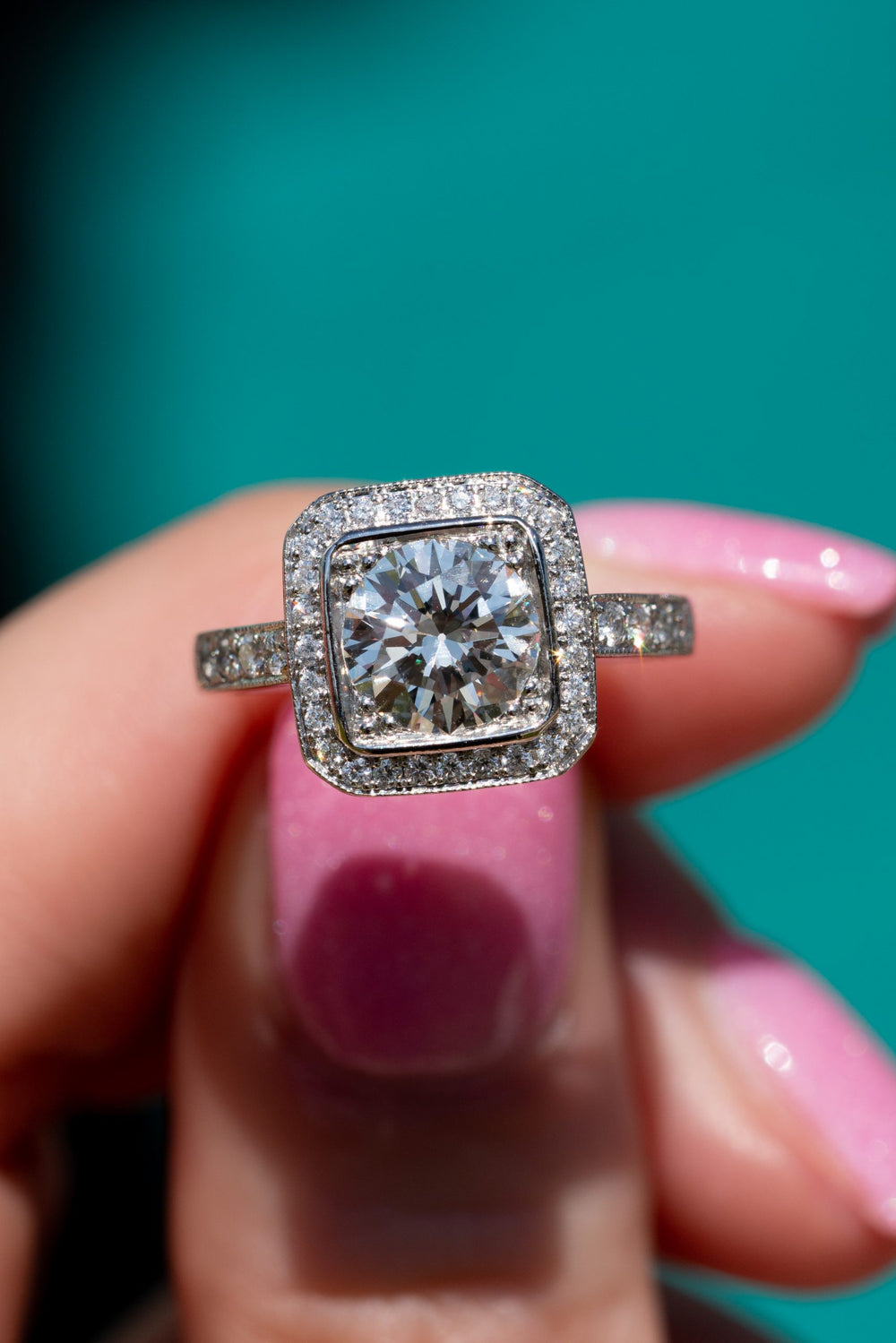 Diamond halo engagement ring held in hand