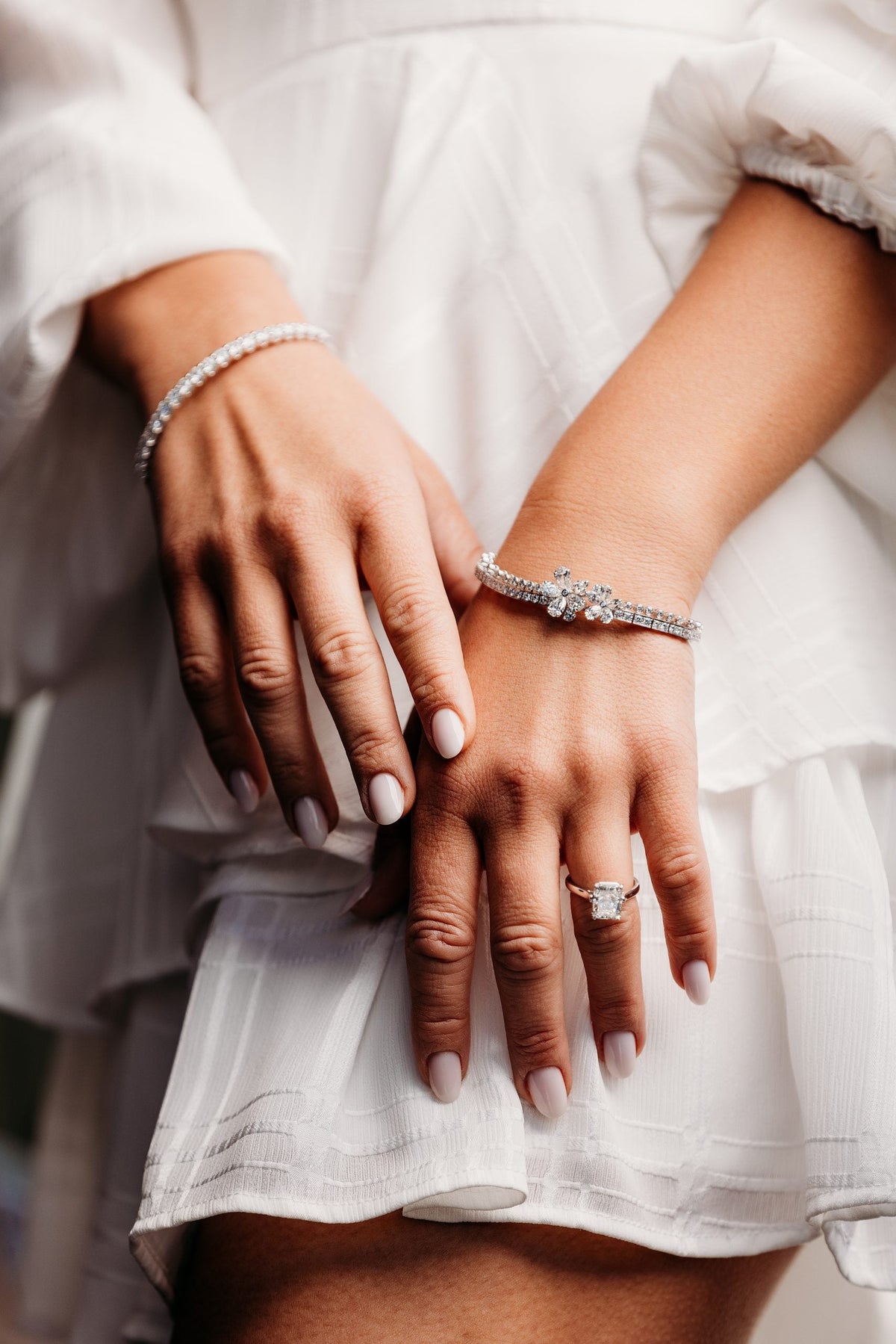 Diamond bracelets and rings worn with a cream blouse