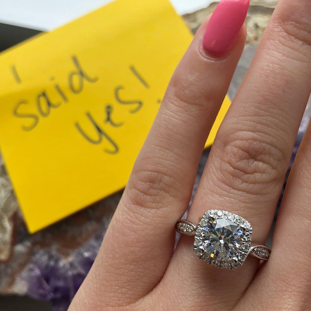 An engagement ring with I said yes in the background.
