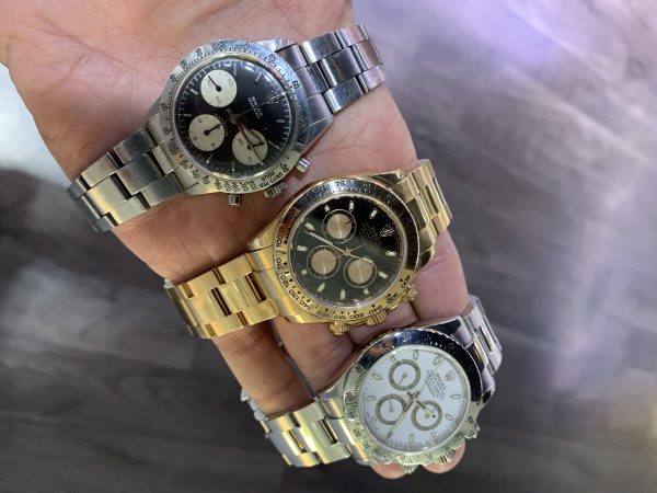 three rolex daytona watches stainless steel with black dial, rose gold with black dial and stainless steel with white dial