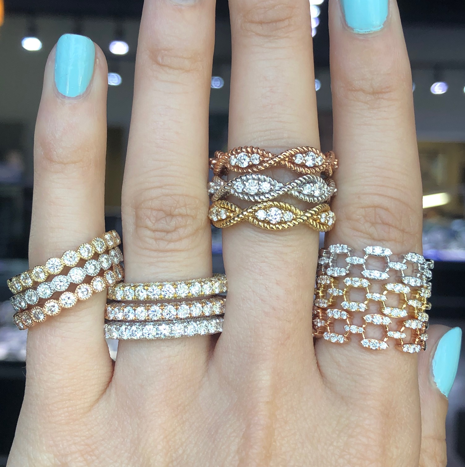 close up of four different diamond wedding ring stacks on left hand