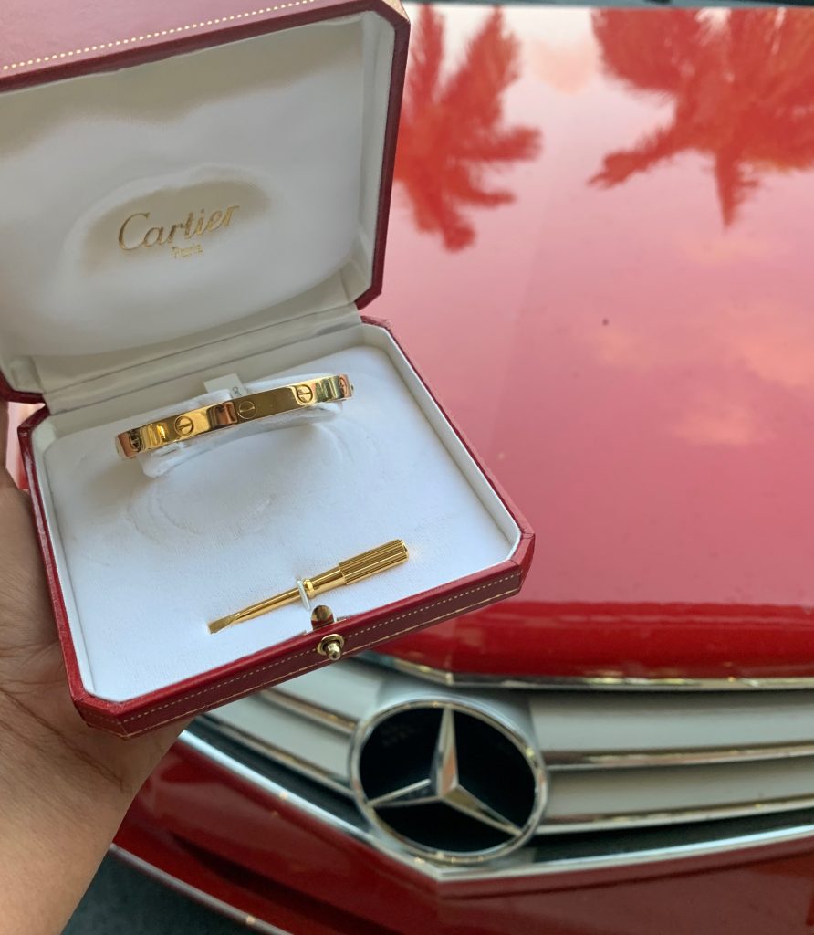 cartier bracelet held in front of red mercedes