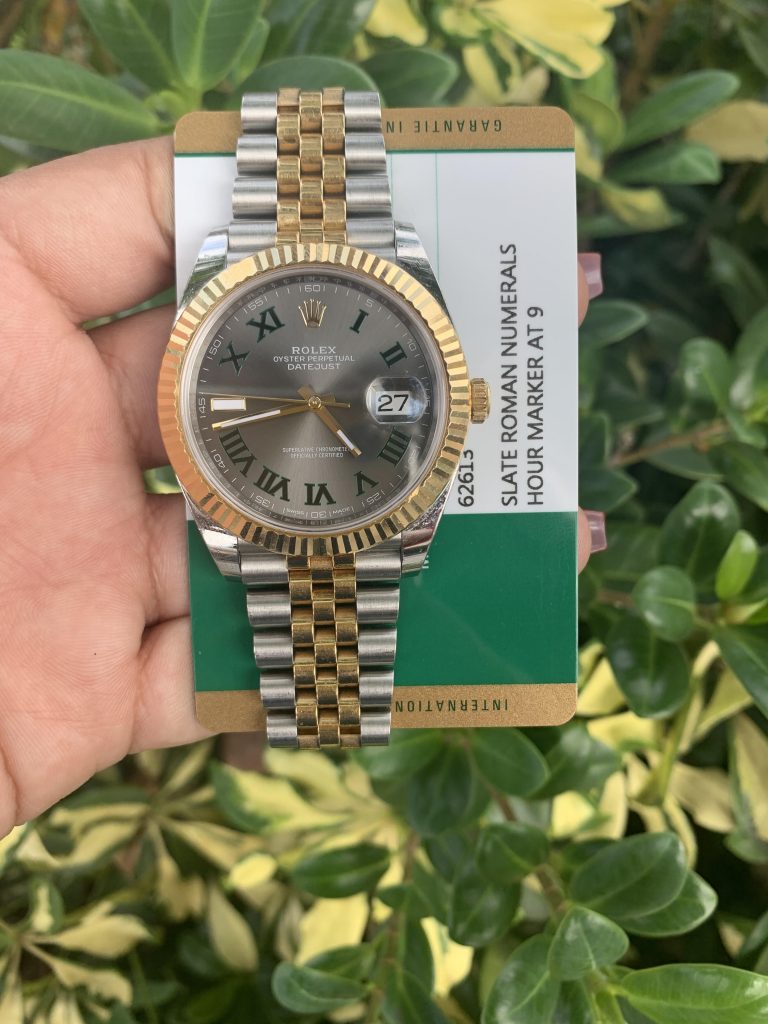 jubilee bracelet rolesor  Rolex Oyster Perpetual Datejust watch with silver dial and gold fluted bezel and roman numeral markers held up with warranty card