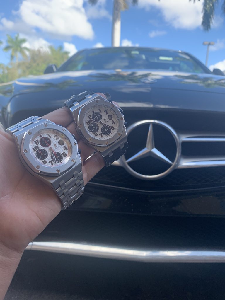Pre owned luxury watch held up next to mercedes benz