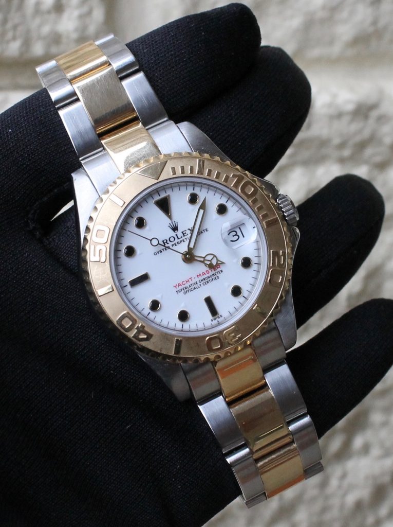 pre owned rolex watch held up Yachtmaster two tone white dial 