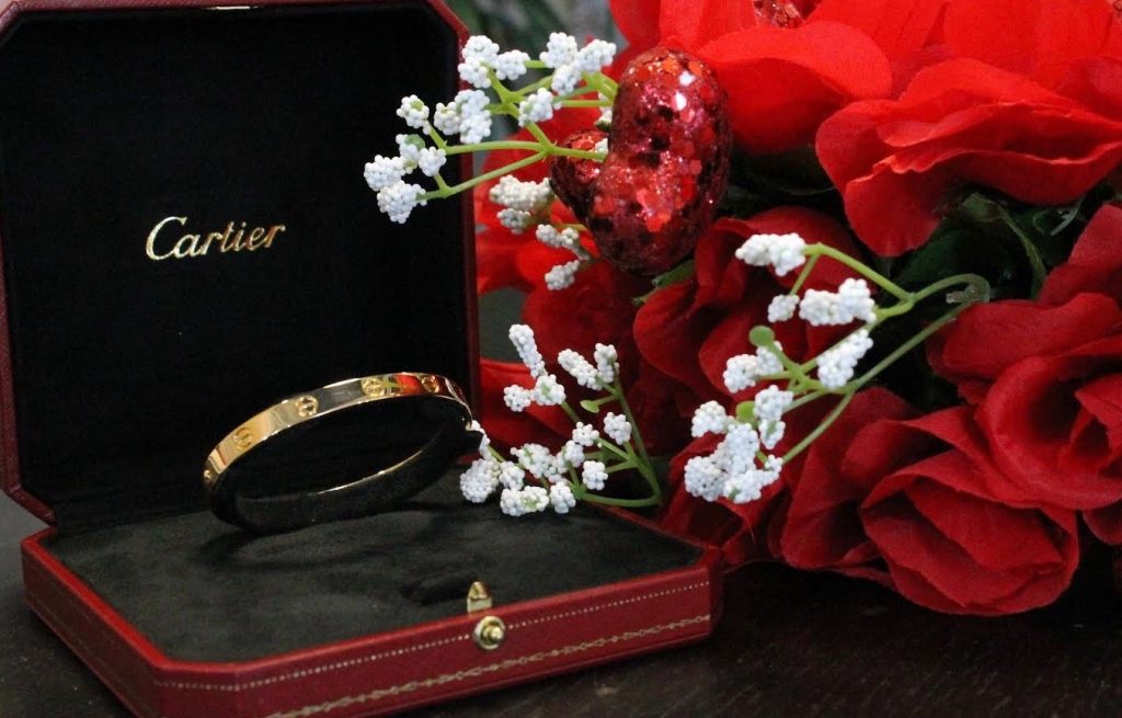 cartier love bracelet in box next to flowers 