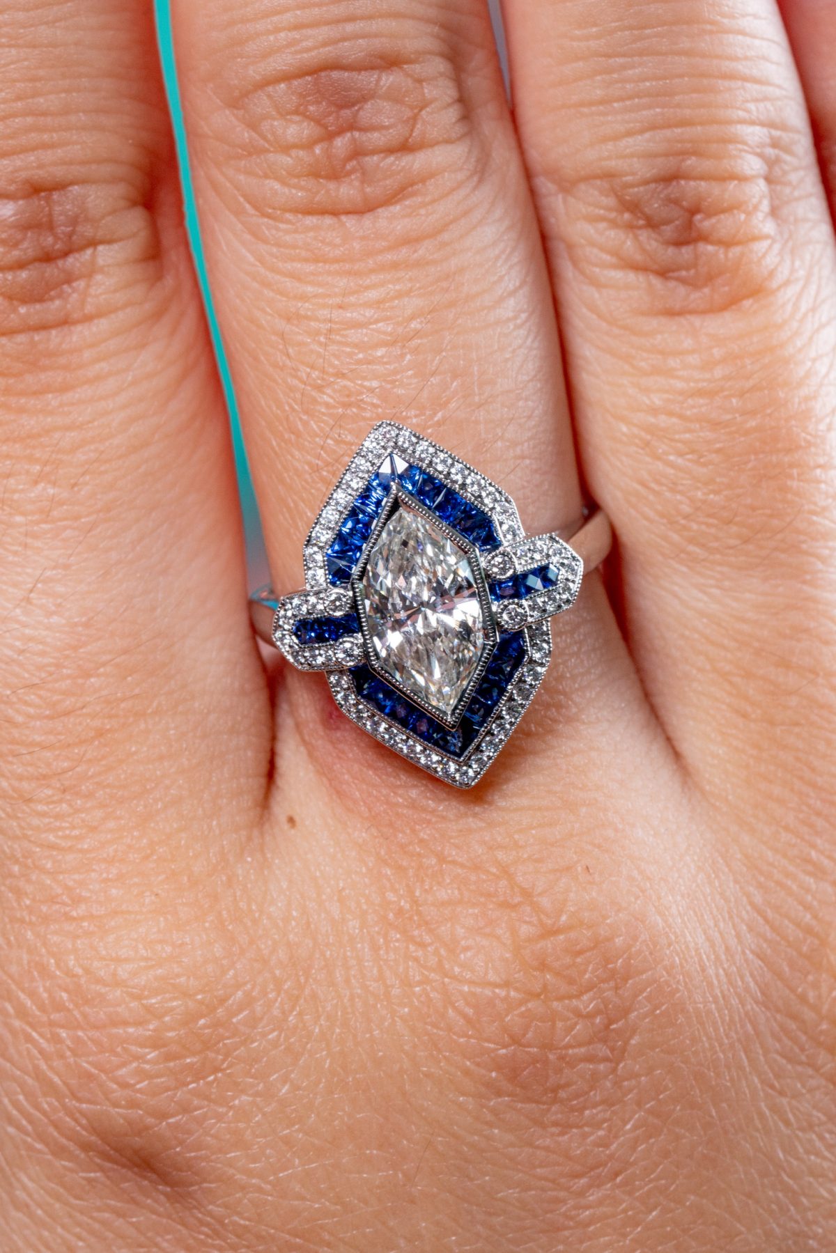 the marquise diamond and sapphire vintage ring on a finger