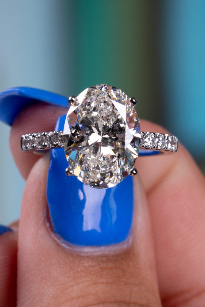 an oval cut ring with hidden halo on a lady’s finger
